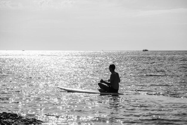 Seitenansichtfoto eines Mannes, der auf dem SUP-Board schwimmt und sich entspannt sportlicher Mann im Meer auf dem Stand