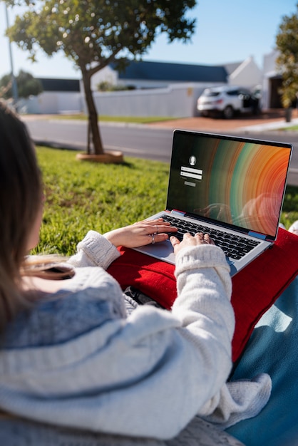 Seitenansichtfrau, die draußen Laptop benutzt