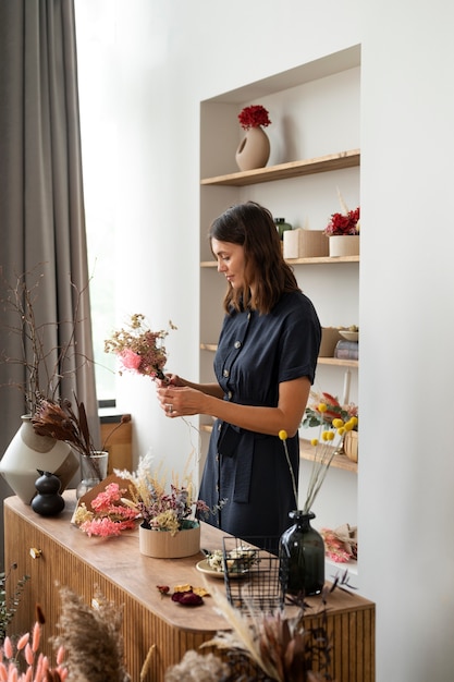 Foto seitenansichtfrau, die mit getrockneten blumen arbeitet