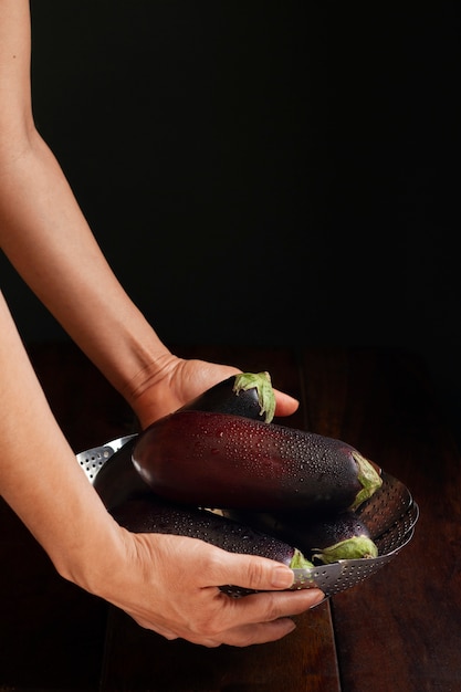 Foto seitenansichthände, die auberginen halten