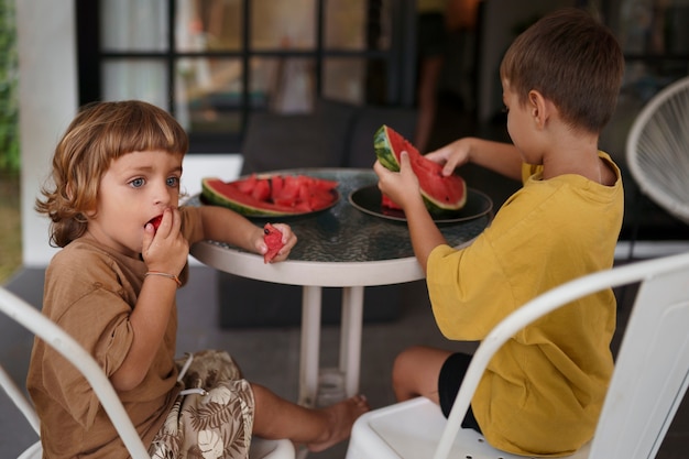 Foto seitenansichtkinder, die wassermelone essen