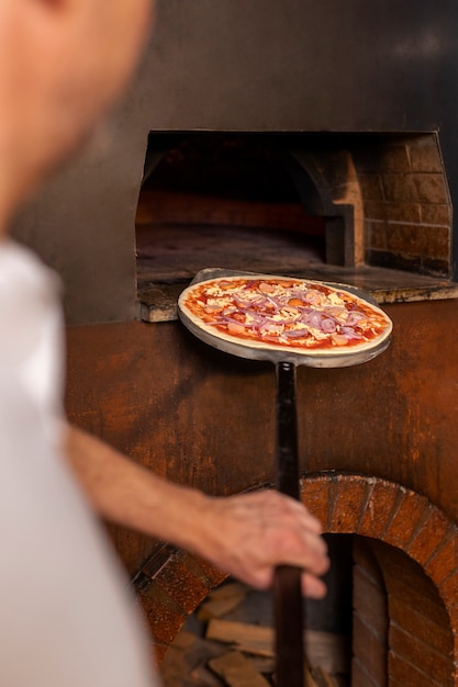 Foto seitenansichtkoch, der pizza zubereitet