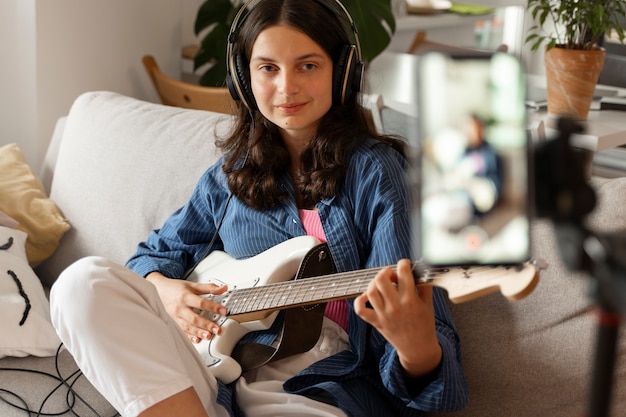 Foto seitenansichtmädchen, das zu hause gitarre spielt