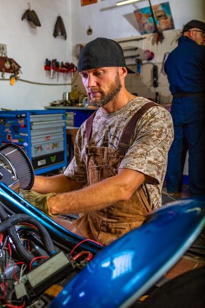 Seitenansichtporträt des Mannes, der in der Garage arbeitet, die Motorrad repariert