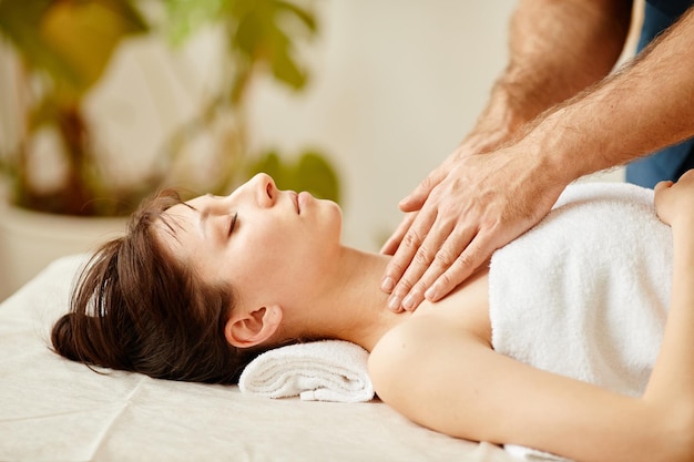 Seitenansichtporträt einer schönen jungen Frau, die eine Gesichtsmassage im Wellnesscenter genießt und mit den Augen liegt