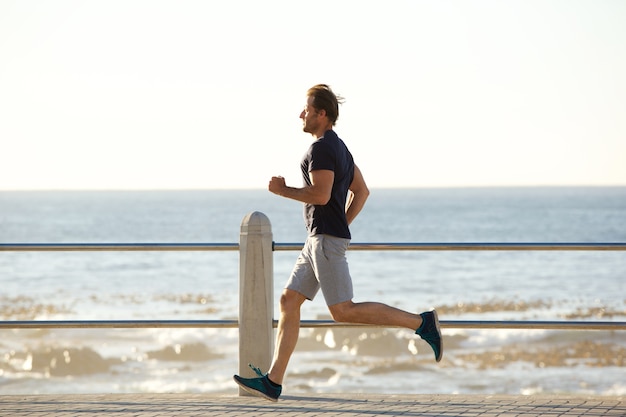 Seitenporträt des aktiven Mannes laufend durch Meer