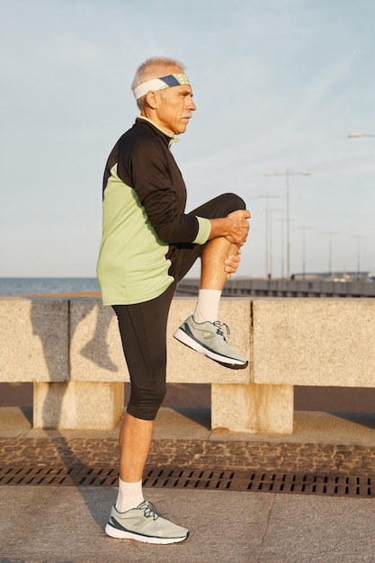 Seitensicht voller Aufnahme eines reifen Mannes, der früh am Morgen im Freien Sport treibt