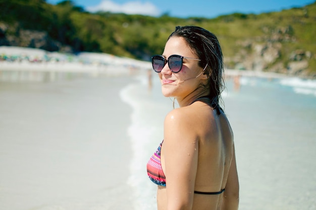 Seitliche Ansicht einer Frau mit Sonnenbrille, die am Strand steht