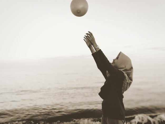 Seitliche Ansicht einer lächelnden reifen Frau, die mit einem Ballon in der Luft spielt