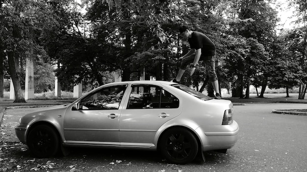 Seitliche Ansicht eines jungen Mannes, der auf ein Auto klettert