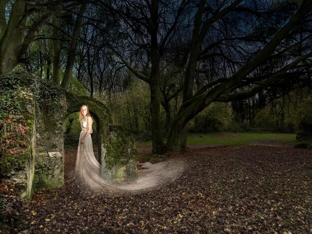 Foto seitliche sicht auf eine frau, die an bäumen im wald steht