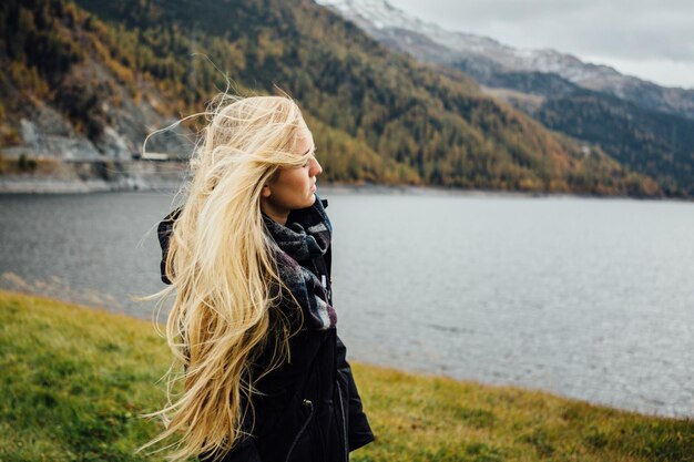 Foto seitliche sicht auf eine junge frau, die am see steht