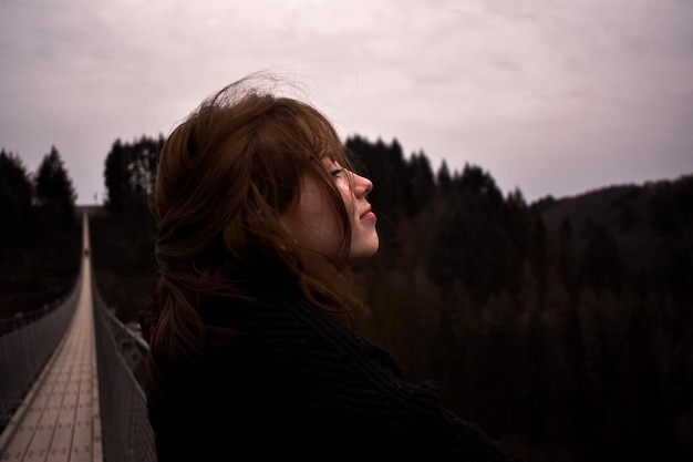 Foto seitliche sicht auf eine junge frau, die gegen den berg wegblickt