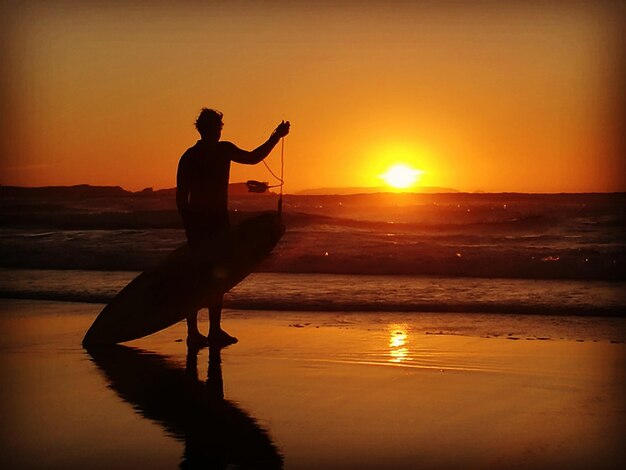 Foto seitliche sicht auf einen silhouettenmann, der bei sonnenuntergang am strand steht