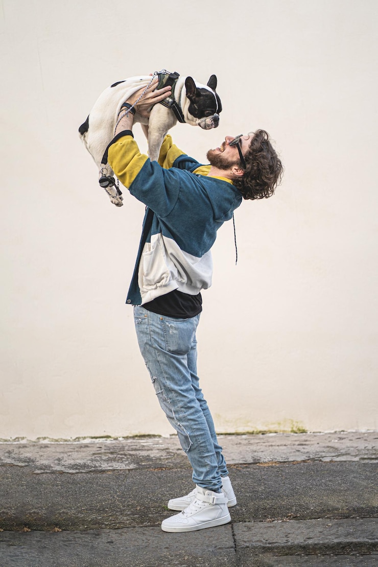 Foto seitliche sicht von einem mann, der einen hund trägt, während er am strand steht