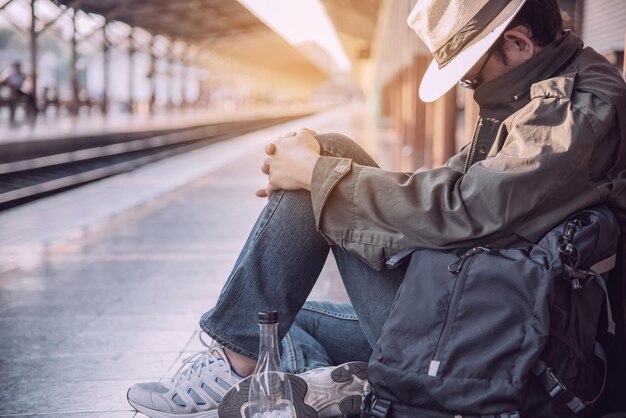 Foto seitliche sicht von einem mann, der schläft, während er auf der bahnhofplattform sitzt