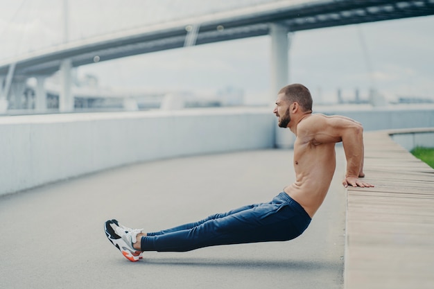 Seitwärts geschossen von muskulösem Mann macht umgekehrte Push-up-Trainingszüge Arme