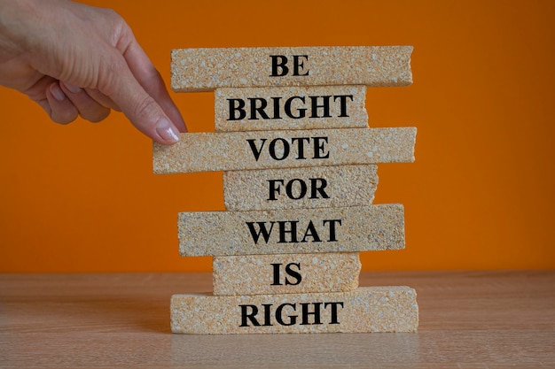 Seja brilhante, vote para o que é certo, palavras em blocos de tijolos, belo fundo laranja, mesa de madeira.