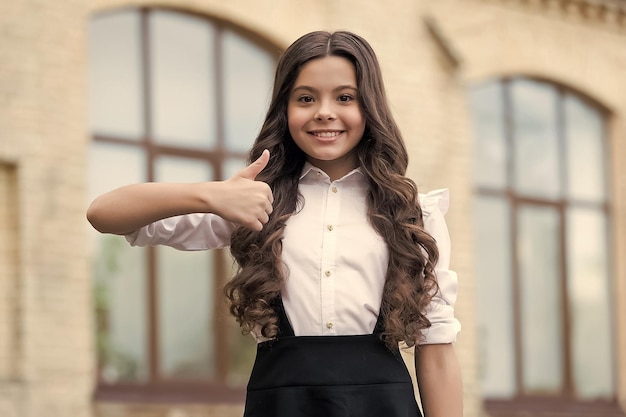 Seja o melhor que você pode ser Criança feliz mostre os polegares para cima ao ar livre Look escolar De volta à moda da escola Educação primária 1º de setembro Dia do conhecimento Polegares para cima se você aprovar