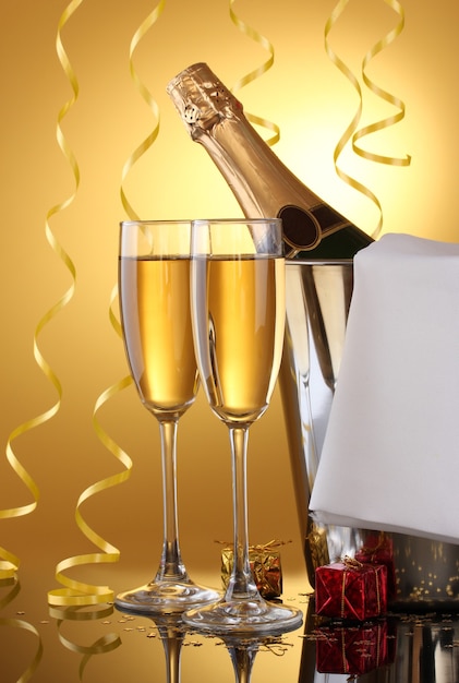 Foto sektflasche im eimer mit eis und gläsern champagner, auf gelbem hintergrund