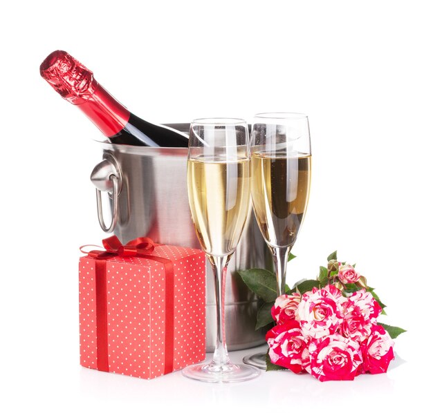 Sektflasche, zwei Gläser, Geschenkbox und rote Rosenblüten. Isoliert auf weißem Hintergrund