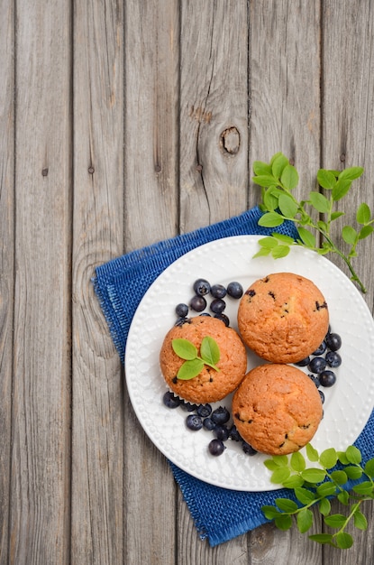 Selbst gemachte Blaubeermuffins auf rustikalem hölzernem Hintergrund, Draufsicht, Ebenenlage, Kopienraum.