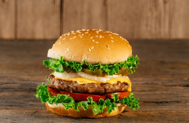 Selbst gemachte Burger mit Salat, Speck, hölzernes Brett der Koteletts