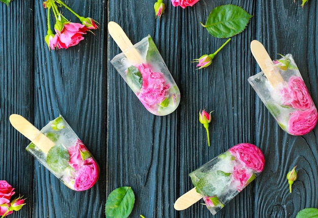 Foto selbst gemachte eisknalle mit blumen auf hölzernem hintergrund