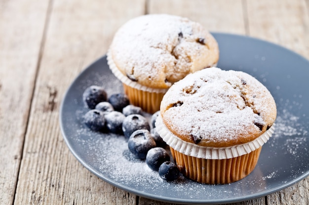 Selbst gemachte frische Muffins mit Zuckerpulver und Blaubeeren.