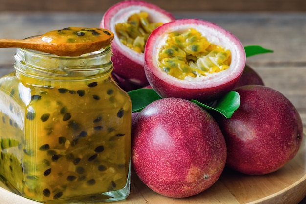 Selbst gemachte köstliche Maracujamarmelade in der Flasche setzte an hölzerne Tabelle nahe frischem Maracuja.