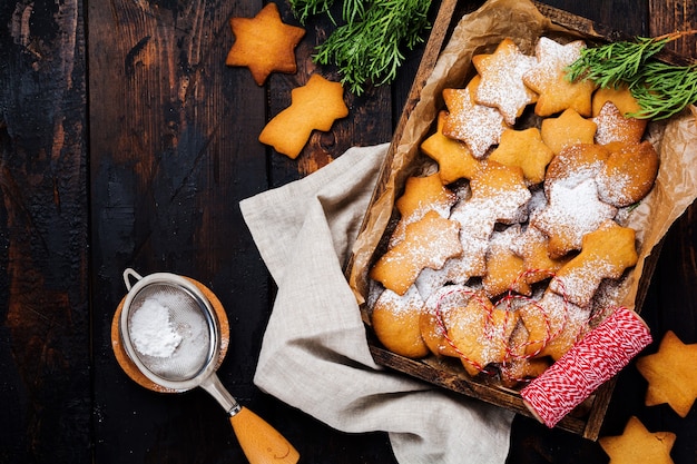 Selbst gemachte Lebkuchenplätzchen der Weihnachtssternform in der Holzkiste auf der alten Holzoberfläche. Draufsicht