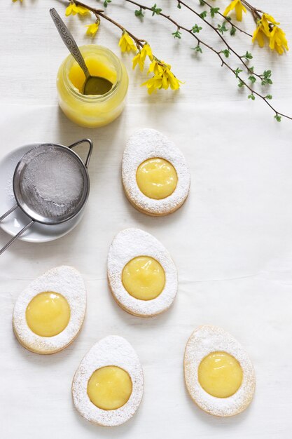 Selbst gemachte ostern-zitronenplätzchen und forsythien, die zweige auf einem hellen hintergrund blühen.