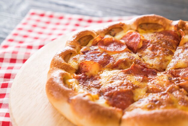 Selbst gemachte Pepperoni Pizza auf hölzerner Platte