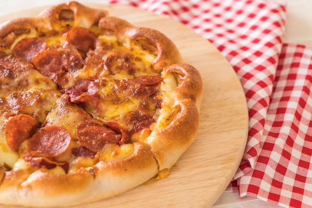 Selbst gemachte Pepperoni Pizza auf hölzerner Platte