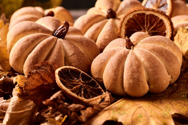 Selbst gemachte Plätzchen in Form des Kürbises im Herbstlaub. Handgemachte Plätzchen Halloweens auf einer Tabelle, Abschluss oben