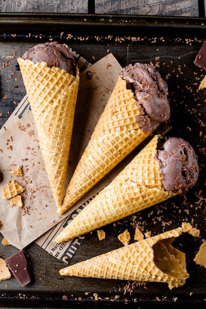 Selbst gemachte Schokoladeneiscreme in den Waffelkegeln auf dunklem Metallhintergrund. Sommernachtisch. Ansicht von oben