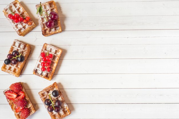 Selbst gemachte Waffeln mit Sommerbeeren auf einem Leuchtpult. Tiefenschärfe