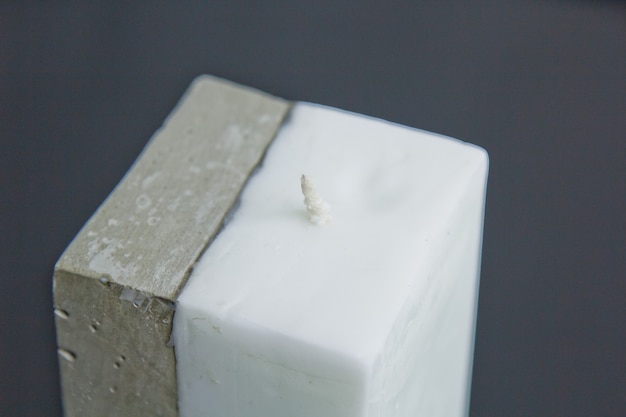 Selbst gemachte weiße Kerze mit Beton auf der Oberfläche einer weißen Wand