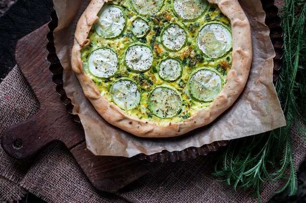 Selbst gemachte Zucchini-Ziegenkäse-Torte auf einem dunklen rustikalen Holzbretthintergrund