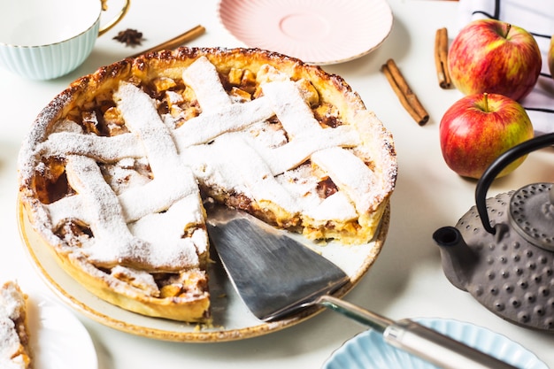 Selbst gemachter Apfelkuchen besprüht mit Puderzucker mit einem geschnittenen Stück