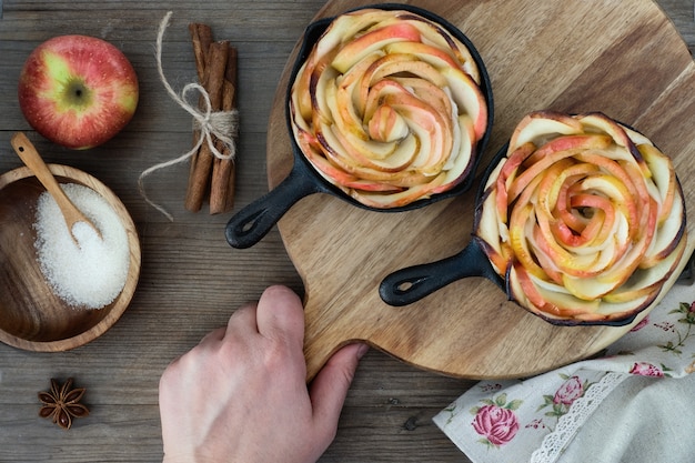 Selbst gemachter blätterteig mit den rosafarbenen geformten apfelscheiben, die in den eisenbratpfannen gebacken werden