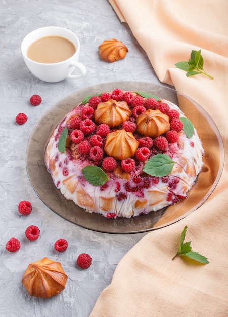 Selbst gemachter Geleekuchen mit Milch, Plätzchen und Himbeere mit Tasse Kaffee und orange Gewebe, Seitenansicht.