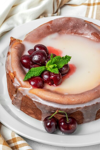 Selbst gemachter Käsekuchen mit Kirschen und Minze auf weißem Hintergrund