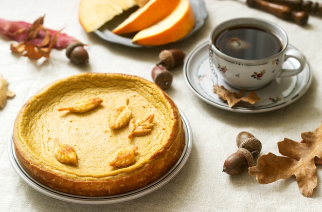 Selbst gemachter Kuchen des traditionellen amerikanischen Kürbises, verziert mit Plätzchen auf einem Hintergrund von Kürbisen und von Herbstlaub.