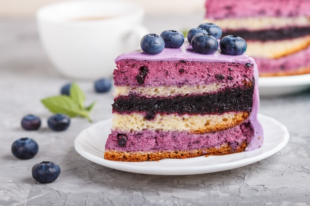 Selbst gemachter Kuchen mit Auflaufcreme und Blaubeermarmelade mit Tasse Kaffee auf einem grauen konkreten Hintergrund