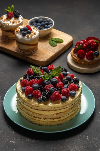 Selbst gemachter Kuchen mit frischen Beeren und süßen Desserts auf dunklem Hintergrund.