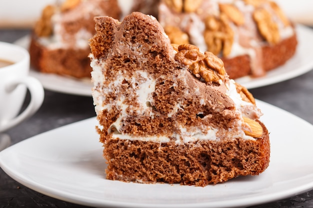 Selbst gemachter Kuchen mit Milchcremekakaomandelhaselnuss auf einem schwarzen konkreten Hintergrund und einem Tasse Kaffee