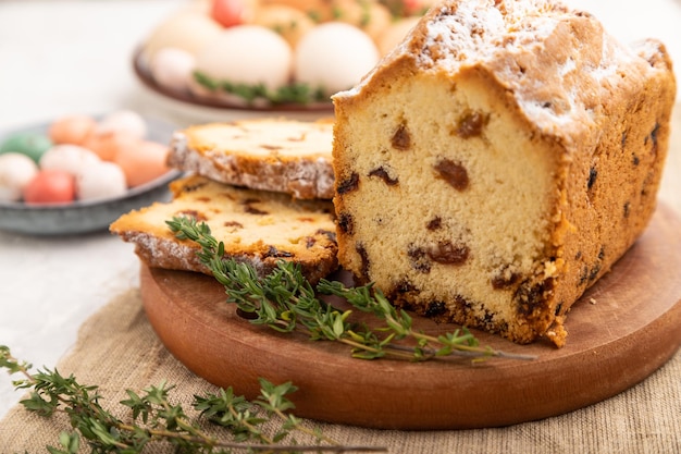 Selbst gemachter Osterkuchen mit Rosinen und Eiern auf Platte auf einem selektiven Fokus der grauen konkreten Hintergrundseitenansicht