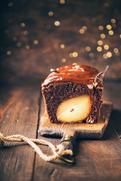 Selbst gemachter Schokoladenkuchen mit Birne an der rustikalen Holzoberfläche mit Bokeh. Weihnachts-Brownie mit Fudge. Selektiver Fokus.