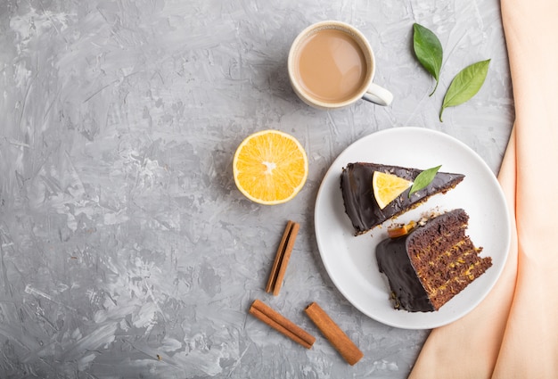 Selbst gemachter Schokoladenkuchen mit Orange und Zimt mit Tasse Kaffee auf grauem Betonhintergrund. Draufsicht, Kopierraum.